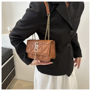 Gros plan sur le sac matelassé marron avec chaîne dorée et détail de gland élégant
