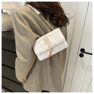 Détail du sac bandoulière matelassé blanc avec chaîne dorée et élégant pompon décoratif