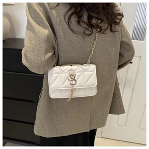 Détail du sac bandoulière blanc matelassé avec chaîne dorée et boucle à franges en S