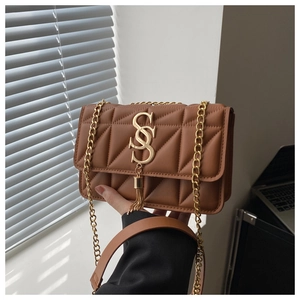Détail d'un sac matelassé marron en similicuir avec chaîne dorée et logo en métal