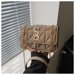 Détail du sac matelassé beige avec logo S doré, pompon et bandoulière en chaîne
