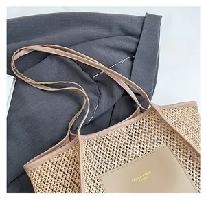 Detail of woven straw tote bag featuring brown leather straps and fashion leather patch