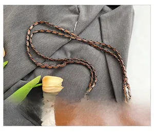 Detail of woven chain strap and plush trim on brown leather shoulder bag for women