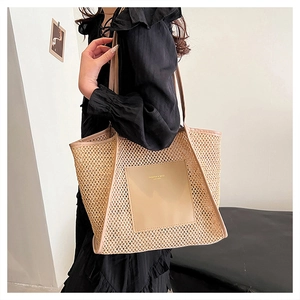 Detail of woven straw tote bag with beige leather trim shown on a black dress model