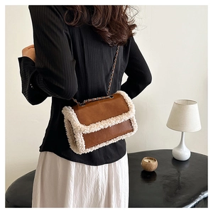 Detail of plush sherpa trim on brown leather shoulder bag with chain strap