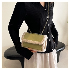 Detail of green patent leather crossbody bag with cream faux shearling trim and chain strap