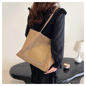 Macro detail of hand-woven straw tote bag featuring leather patch and sleek shoulder straps
