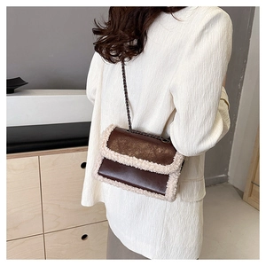 Detail of a brown leather shoulder bag with white faux fur trim and gold chain strap