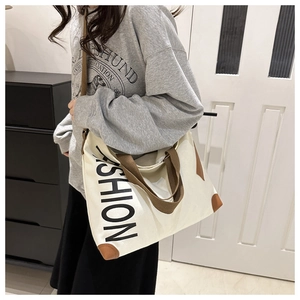 Detail of canvas tote bag showing fashion lettering and brown reinforced leather corners