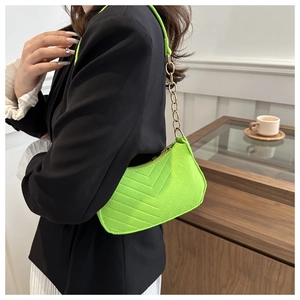 Neon green baguette bag with V-quilt pattern and gold chain strap shown on model