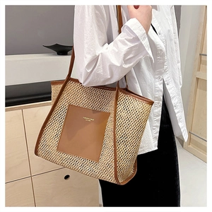 Dettaglio di una borsa tote intrecciata con finiture in pelle marrone indossata da modella
