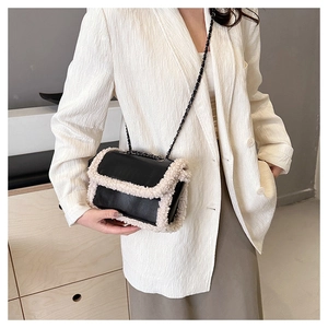 Detail of a vintage crossbody bag with black leather and cream fleece trim on a model