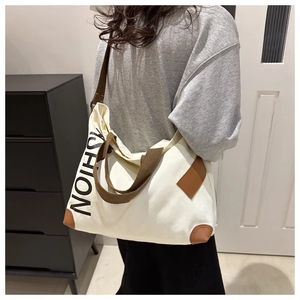 Detail of canvas tote bag with brown straps and vertical FASHION print on white fabric