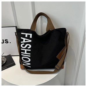 Detail of black canvas tote showing fashion print and durable brown shoulder straps