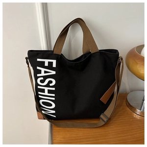 Detail of black canvas tote bag with FASHION print and reinforced leather corners