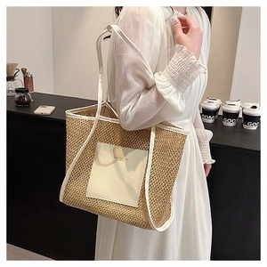 Dettaglio di una borsa tote in paglia intrecciata con cinturini in pelle color crema