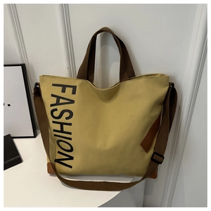 Detail of reinforced leather corners and woven straps on mustard yellow canvas tote bag
