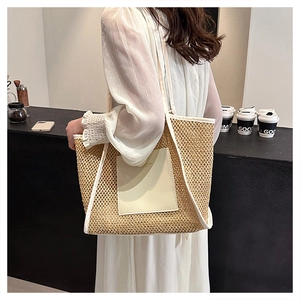 Detail view of woven straw tote bag with white leather straps and trim on model