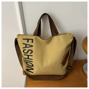 Detail view of mustard yellow canvas tote bag with brown straps and FASHION logo