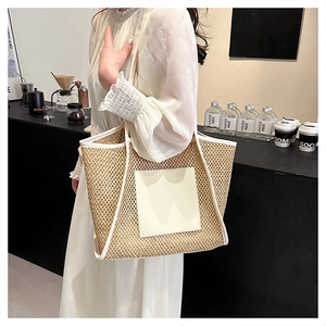 Dettaglio borsa tote in paglia intrecciata con cinturini in pelle bianca in caffè