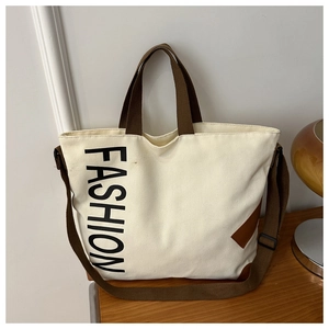 Detail of canvas tote with brown straps and FASHION print on a wooden table