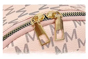 Close-up of golden dual-zipper closure on pink pebble leather bag with M pattern