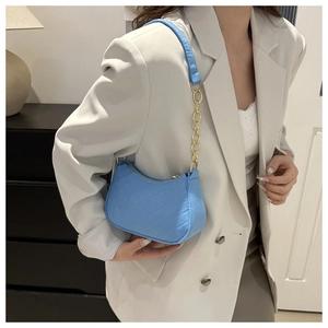 Sky blue quilted leather underarm bag with gold chain strap on model in white suit