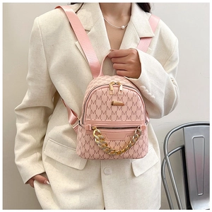Detail of pink mini backpack with M-letter monogram and gold chain decoration