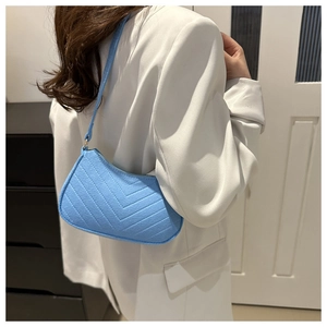 Detailed view of light blue quilted underarm bag in textured felt worn by a model