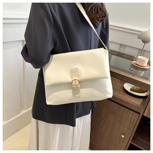 Detail view of cream crossbody bag with gold clasp shown on model with blue blazer