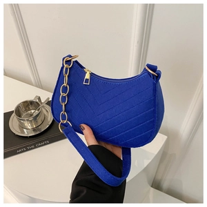 Detailed shot of cobalt blue quilted crescent bag with gold chain and woven strap