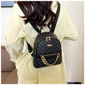 Mini black backpack with grey M-letter print and decorative gold chain on model