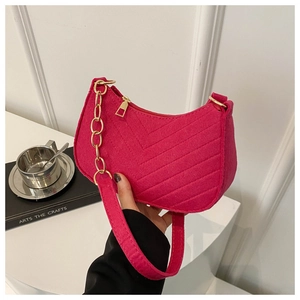 Detailed texture of fuchsia quilted wool bag with bold gold chain strap and metal zipper