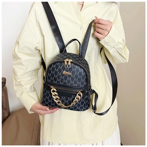 Close-up of a black mini backpack featuring grey letter M monogram and gold metal chain