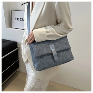 Retro grey matte tote bag with blue leather trim and wide strap on a fashion model