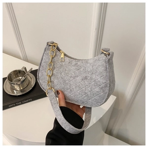 Detail of grey felt baguette bag with diagonal quilting and golden chain strap