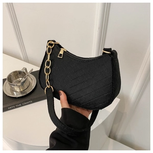 Detail of black crescent shoulder bag with quilted texture and gold chain strap