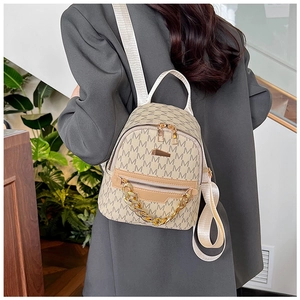 Detail of mini backpack with beige monogram pattern and gold chain decorative strap