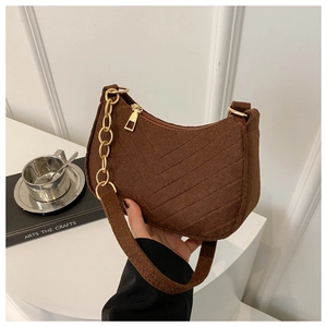 Close-up of brown felt crossbody bag with quilted texture and gold chain strap detail