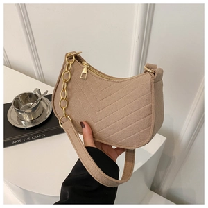 Close-up of camel quilted crossbody bag with V-stitch texture and gold chain detail