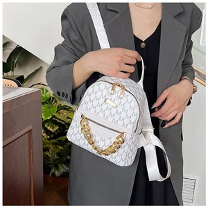 Close-up of stylish mini white backpack with M-pattern and gold chain detail on model
