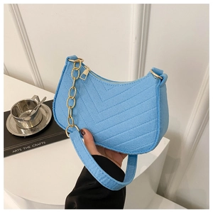 Detail of light blue textured shoulder bag with V-shaped quilting and gold chain