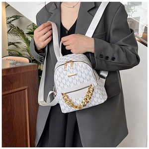 Close-up of a white mini backpack with gray M patterns and trendy gold chain detail