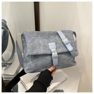 Detail of grey textured crossbody bag featuring light blue strap and gold metal buckle