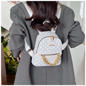 Close-up of white mini backpack with grey M-pattern and chunky gold chain detail