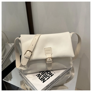 Close-up of creamy white lychee grain leather crossbody bag with metallic buckle detail