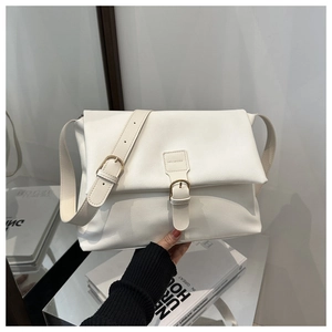 Detail of cream white leather crossbody bag with belt buckle and envelope flap design
