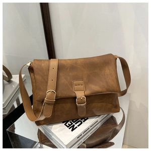 Close-up of vintage brown leather handbag with gold buckle on white books