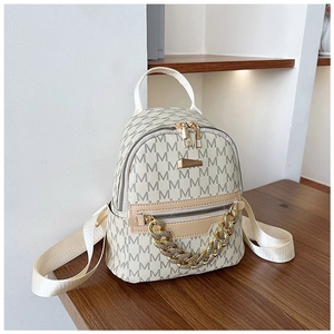Detailed view of mini beige backpack with gold chain accent and repeating M-letter print