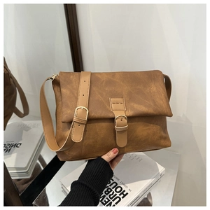 Close-up of vintage brown PU leather crossbody bag with decorative buckles and flap closure